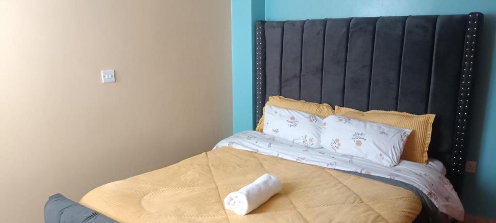 a bed with a black headboard and pillows on it at 2 Bedroom at Kamakis near Greenspot Long term 5 days plus in Ruiru