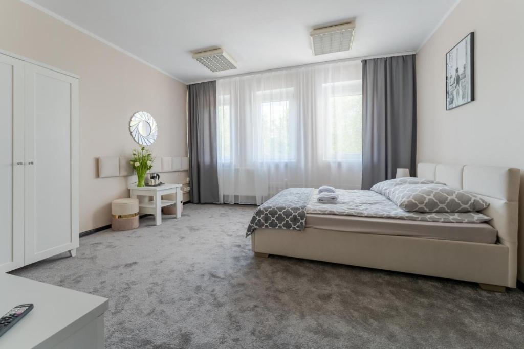 a white bedroom with a large bed and windows at Hostello - Pokoje, Bilard, Ping-Pong, Parking - by SpaceApart in Jelenia Góra