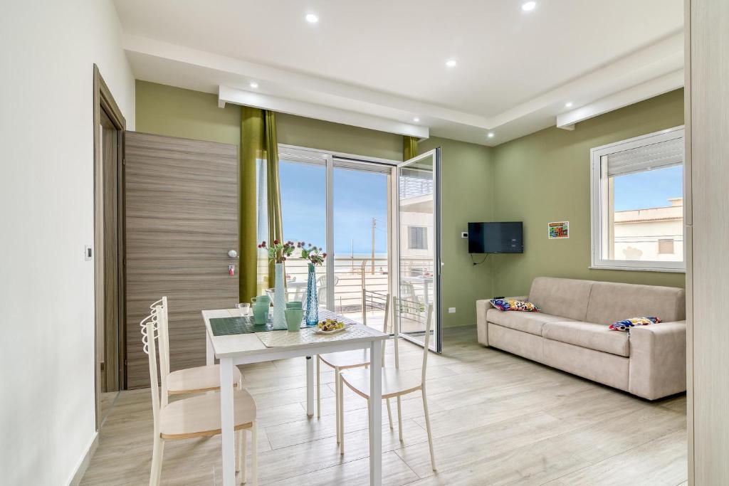 ein Wohnzimmer mit einem Tisch und einem Sofa in der Unterkunft Corallo House 200 mt from the sea - Happy Rentals in Augusta