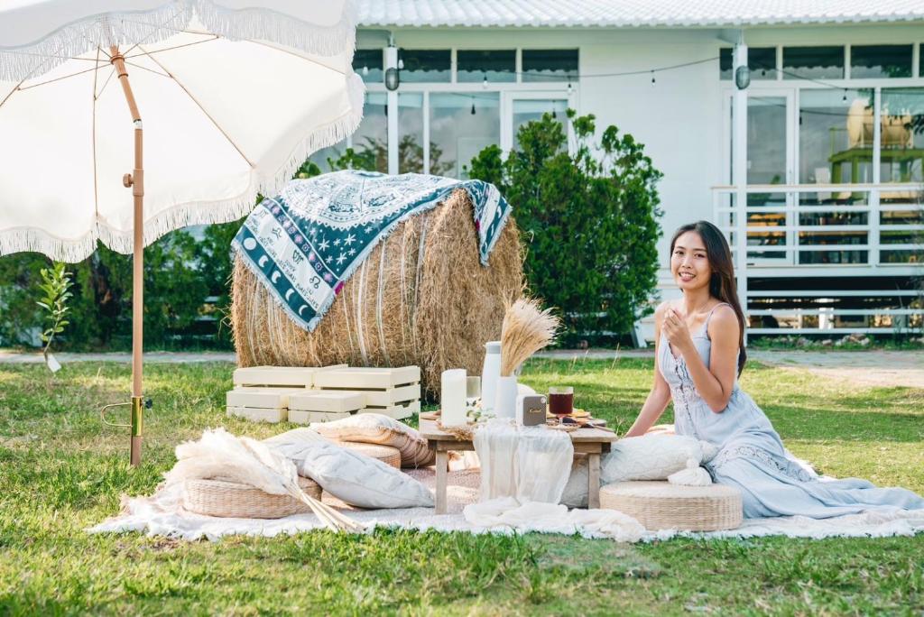 Eine Frau in einem Kleid, die auf einer Picknickdecke sitzt. in der Unterkunft Cape 42 Hotel Ill in Altstadt von Hengchun