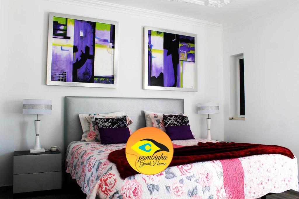 um quarto com uma cama e três pinturas na parede em GuestHouse Pombinha em Nazaré