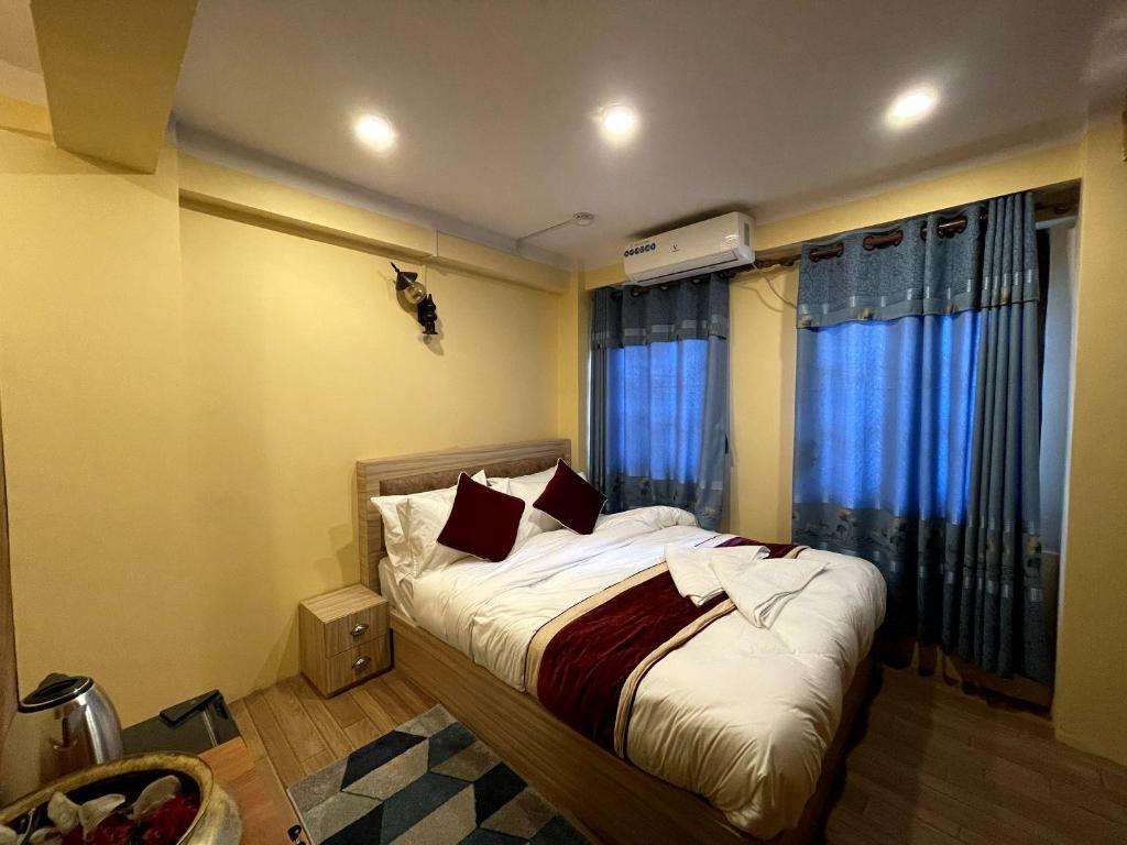 um quarto com uma cama e uma janela com cortinas azuis em Jhigu Chhen em Bhaktapur