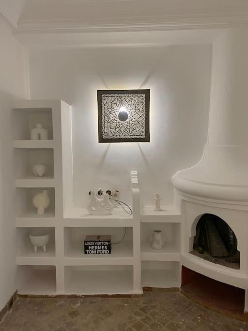 Cette chambre est dotée d'un mur blanc et d'une cheminée. dans l'établissement New private Riad Fiora, à Marrakech
