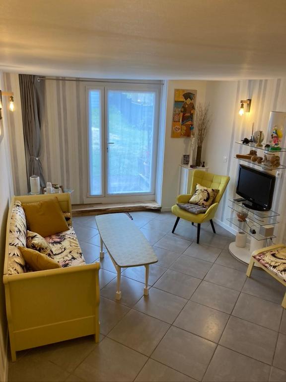 un salon avec un canapé jaune et une table dans l'établissement Doupassage, à La Châtelaine