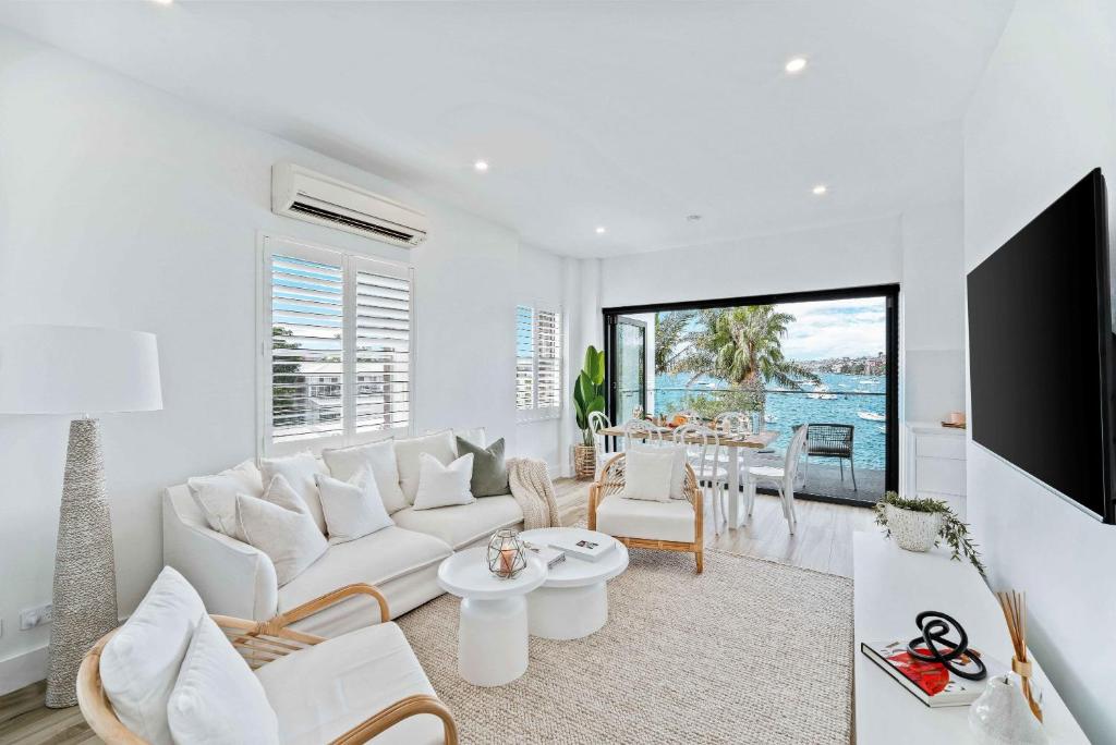ein weißes Wohnzimmer mit einem weißen Sofa und einem Tisch in der Unterkunft Phoenix at Palm View Collective in Sydney