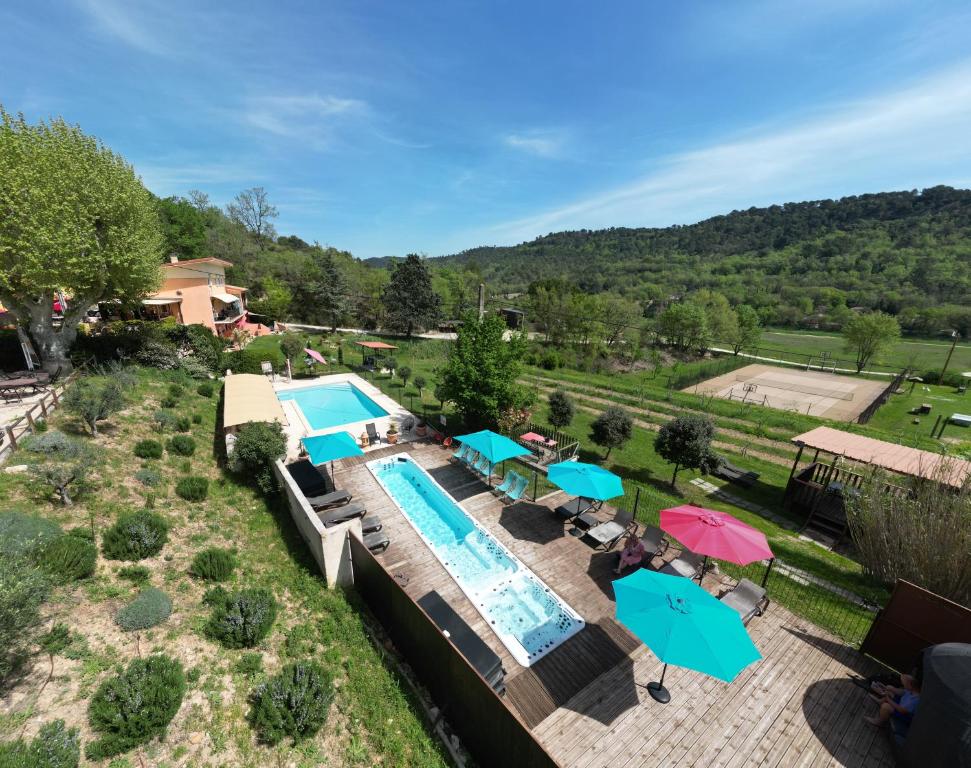 einen Blick über einen Pool mit Sonnenschirmen in der Unterkunft L'Oustaou du Luberon et SPA in Villelaure