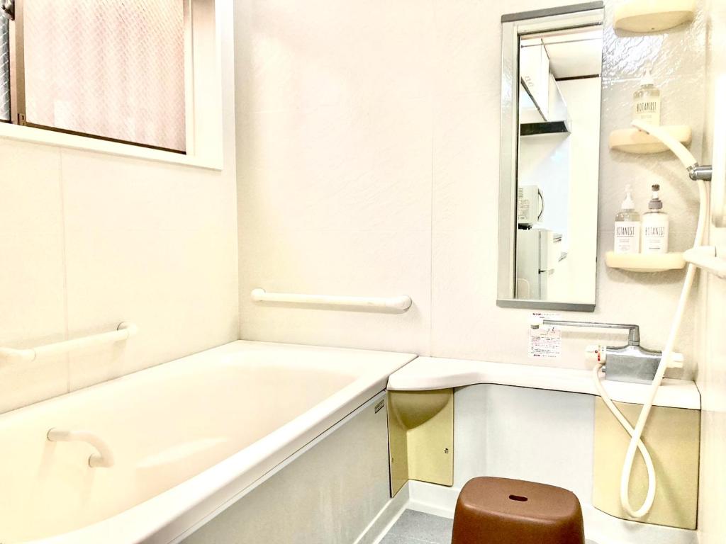 een badkamer met een bad, een wastafel en een spiegel bij KIBA HOUSE in Tokyo