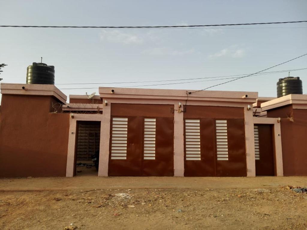 ein braunes und weißes Gebäude mit einer Garage in der Unterkunft FS service in Ouagadougou