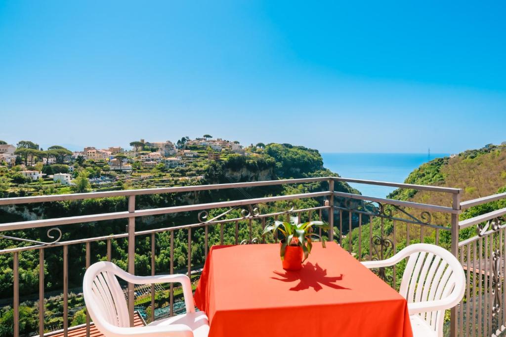 einen roten Tisch und Stühle auf einem Balkon mit Meerblick in der Unterkunft Albergo La Margherita in Scala