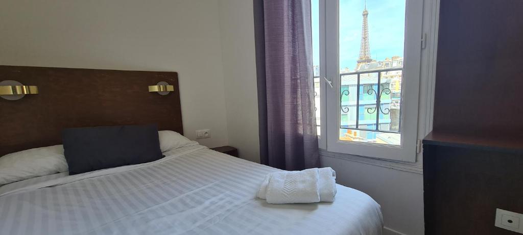 a bedroom with a bed and a window with the eiffel tower at Dupleix Hotel in Paris