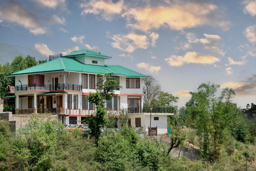 ein Haus mit einem grünen Dach auf einem Hügel in der Unterkunft The Onyx Abode in Dharamsala