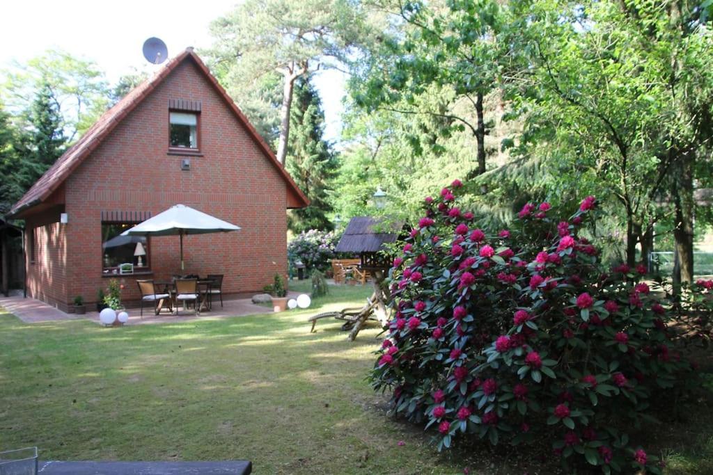 a red brick house with pink flowers in the yard at Ferienhaus am Waldesrand in Hatten