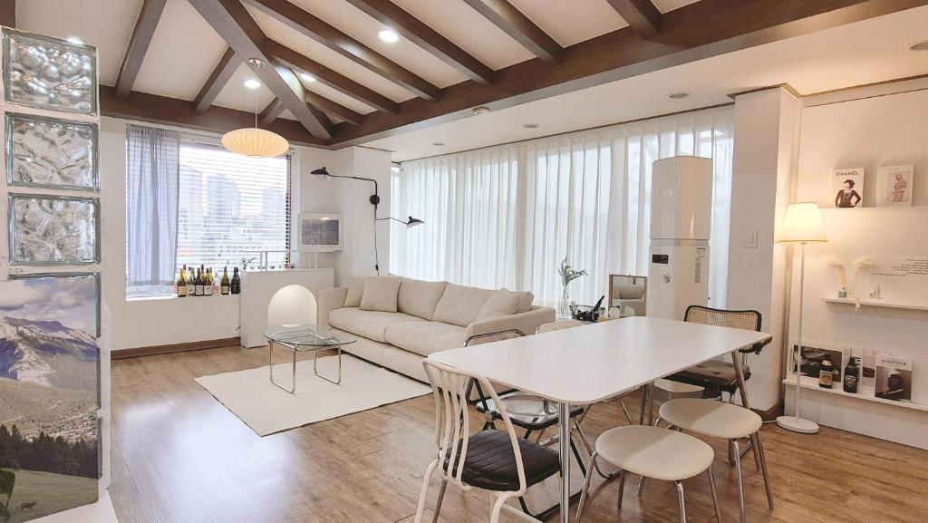 sala de estar con sofá, mesa y sillas en [ COM,A stay] Hongdea St 5min / 3room, en Seúl