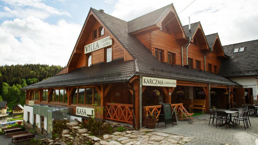 duży drewniany budynek ze stołem przed nim w obiekcie Karczma Czarna Góra - Czarna Góra Resort w Stroniu Śląskim