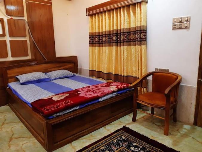 a bedroom with a bed and a chair in it at Jayanta Hotel in Chittagong