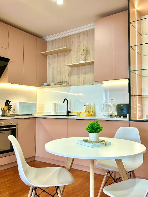 kuchnia z różowymi szafkami, stołem i krzesłami w obiekcie Apartment 39 w Ułan Bator