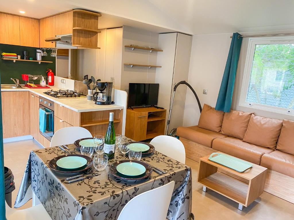a kitchen and living room with a table and a couch at Mobil-home CAMARGUE in Vias