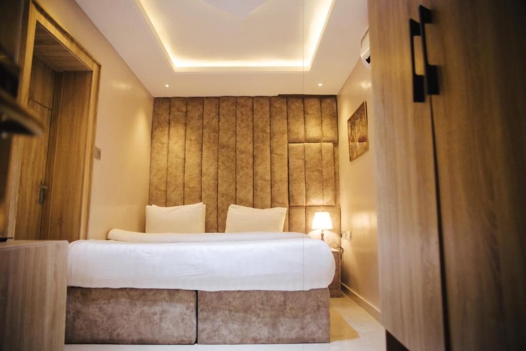 DE LEVERAGE HOTEL & SUITES في لاغوس: غرفة نوم مع سرير أبيض كبير في غرفة
