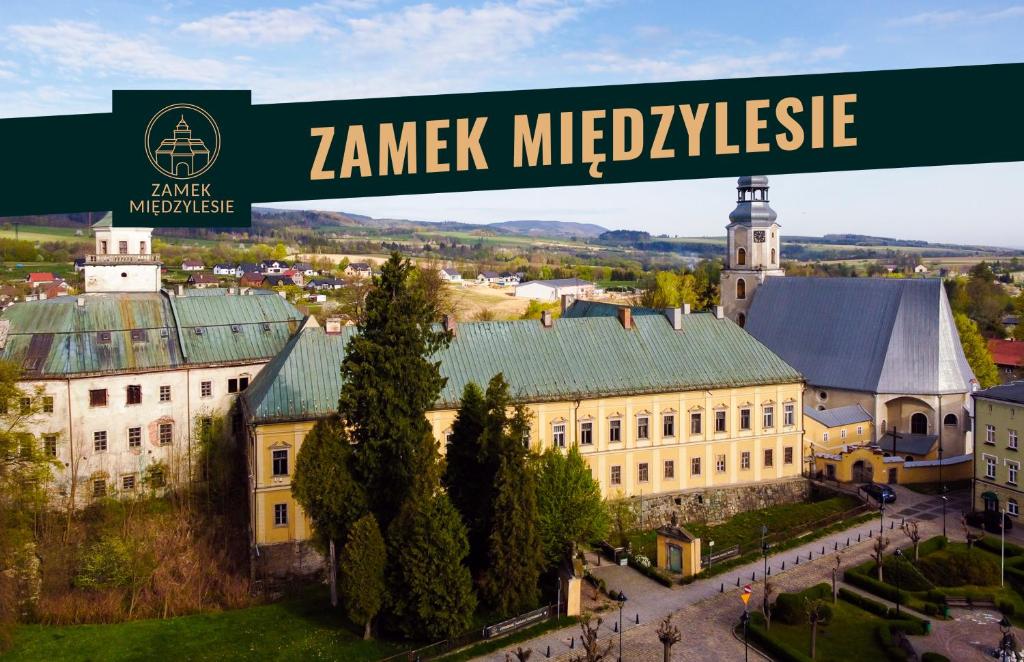 a green street sign above a large building at Zamek Międzylesie in Międzylesie