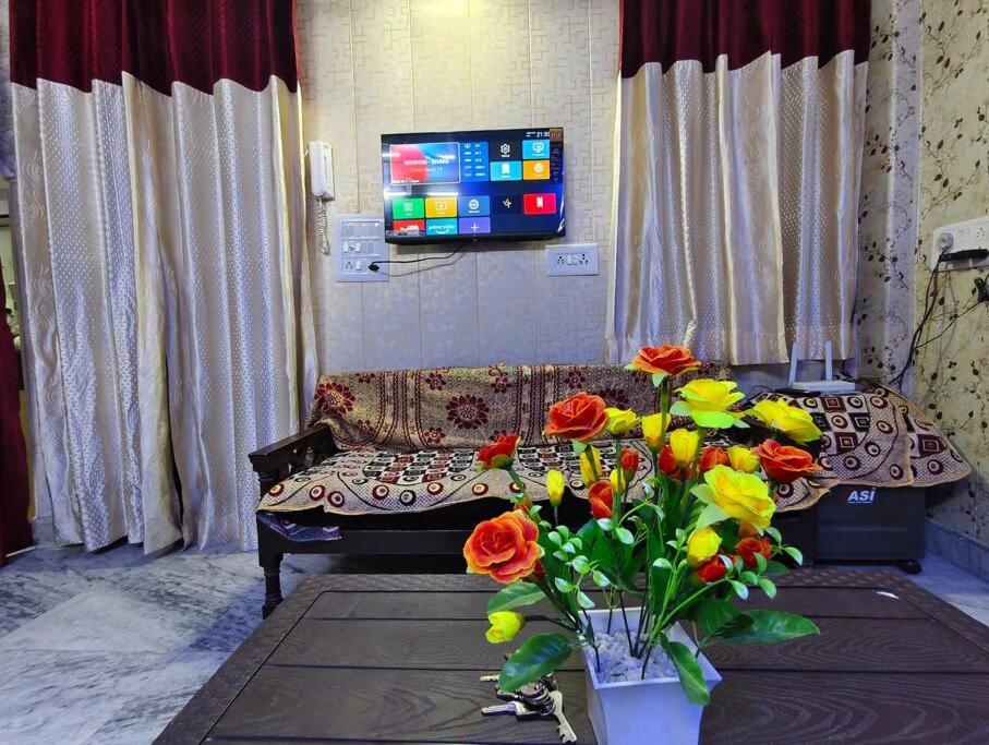 a living room with a couch and flowers and a tv at Peaceful stay in New Delhi