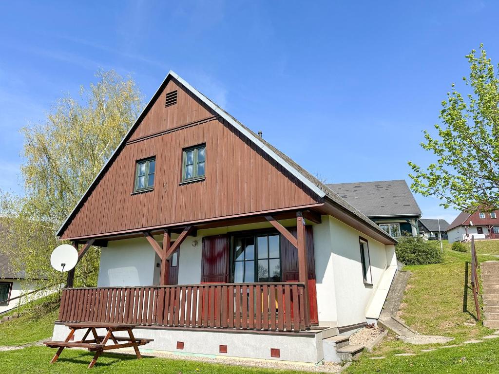 een huis met een houten terras en een bank bij Třicítka na Šťastném kopci in Cerny Dul