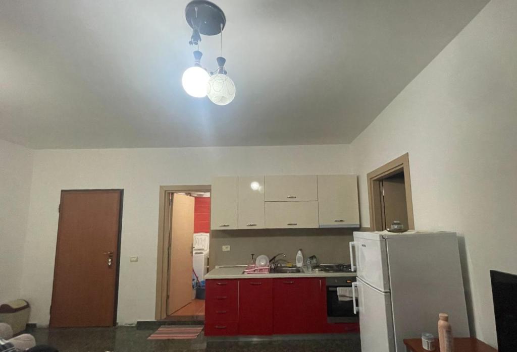 eine Küche mit roten Schränken und einem weißen Kühlschrank in der Unterkunft Shtepi Pushimi in Velipojë