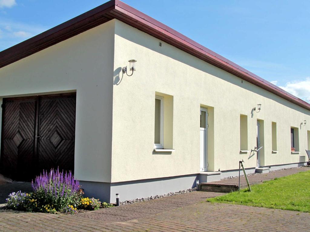 ein großes weißes Gebäude mit großer Garage in der Unterkunft Ferienwohnung Haus Möwe in Freest