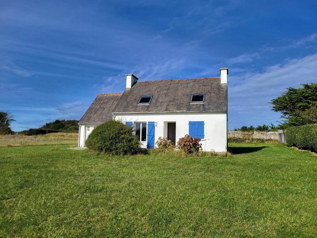 ein weißes Haus mit blauen Türen auf einem Grasfeld in der Unterkunft 625-VIlla Penzer pour surfer a St Tugen in Primelin