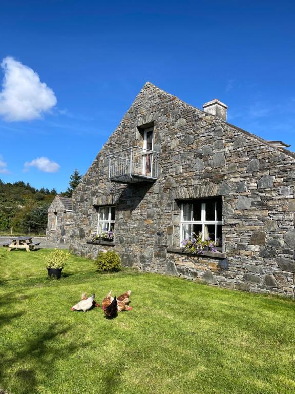 an old stone house with two people laying on the grass at Bed & Breakfast - Shanakeever Farm in Clifden