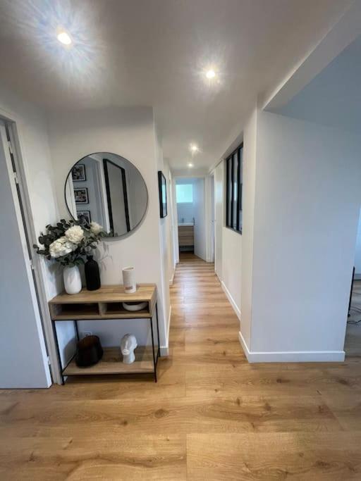 - un couloir d'une maison avec une table et un miroir dans l'établissement Bel appart proche Paris, 3 chambres, Balcon & Parc, à Suresnes