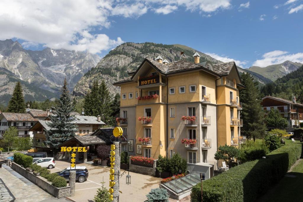 a large building in front of a mountain at Hotel Bouton d'Or - Courmayeur in Courmayeur