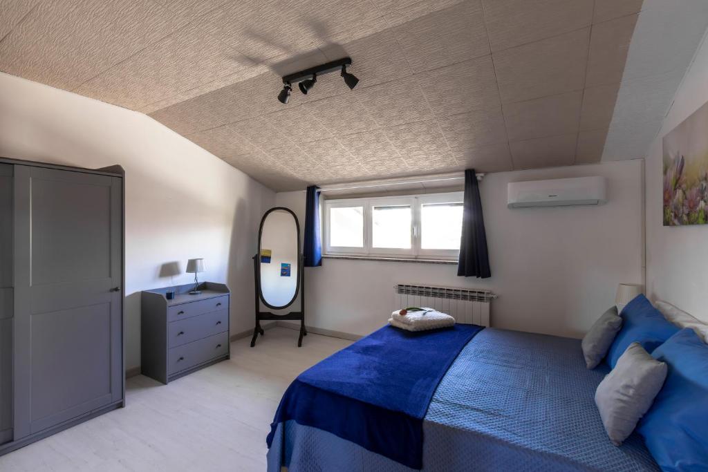 una camera con letto blu e specchio di Stanza in villa da Alberto a San Giorgio Canavese