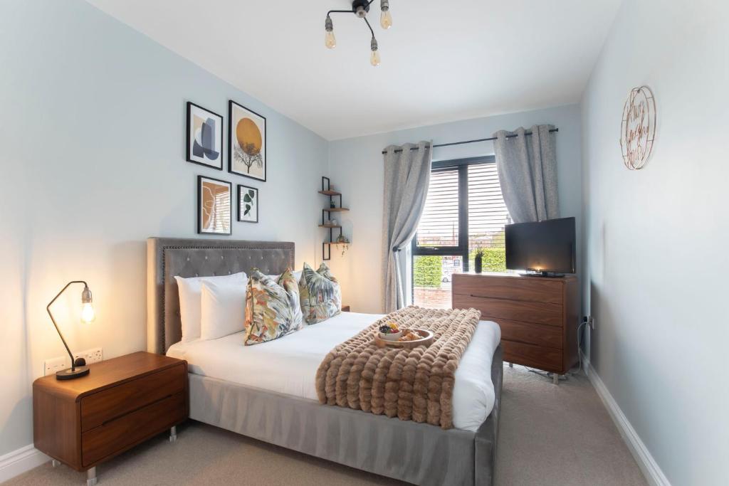 a bedroom with a bed and a tv and a window at Elliot Oliver - Stylish 2 Bedroom Apartment With Parking In The Docks in Gloucester