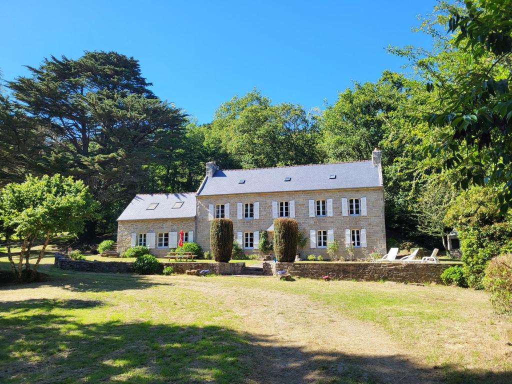 ein großes Steinhaus mit Bäumen im Hintergrund in der Unterkunft 607-Manoir de Pompren in Esquibien