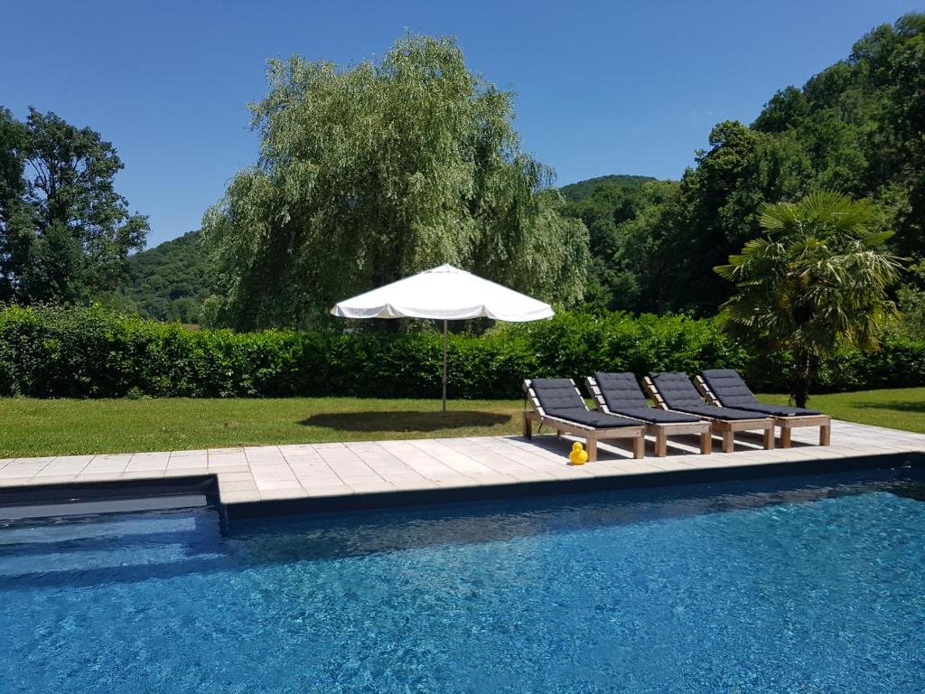 a pool with two lounge chairs and an umbrella at Pyrénées Passions - Gîtes de Charmes &amp; Caractère in Estadens