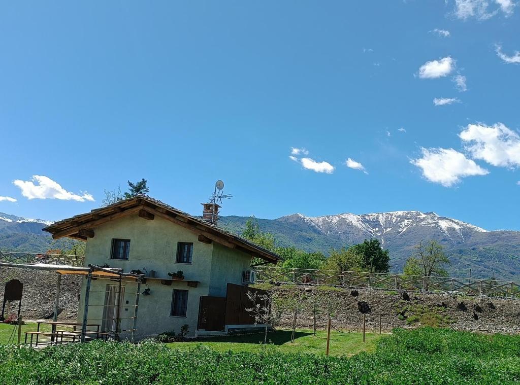 an old house with mountains in the background at 'L ciabot 'd Ginota in Barge