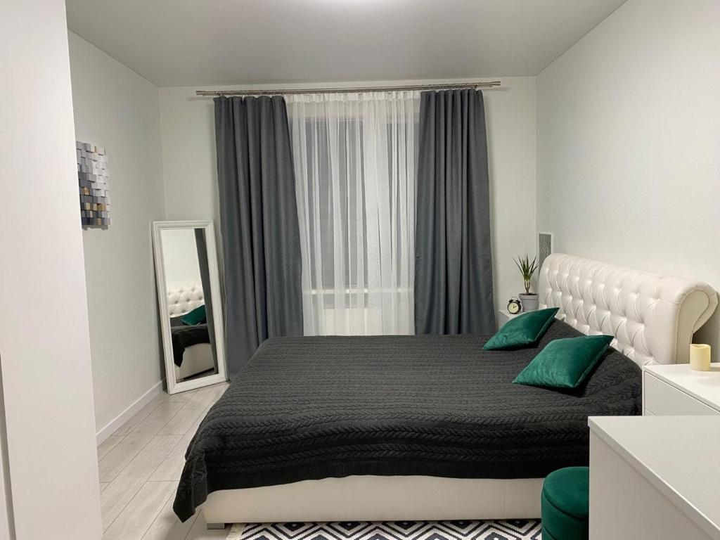 1 dormitorio con 1 cama grande con almohadas verdes en A cosy apartment, en Osh