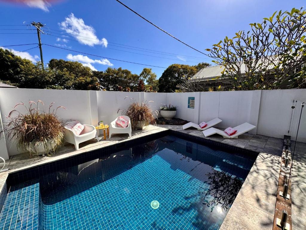 a swimming pool with chairs next to a white fence at Gold Coast-Miami Mid-Century Beach Home With Pool in Gold Coast
