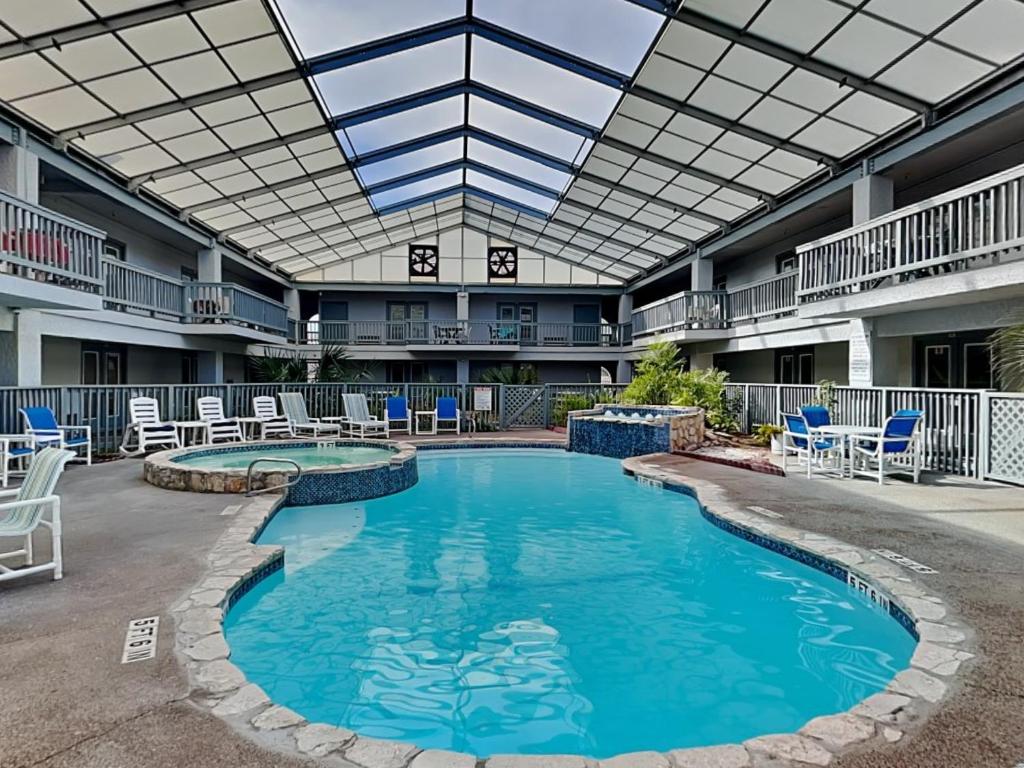 una piscina en un patio con sillas y techo en Sandpiper Shores, en Padre Island