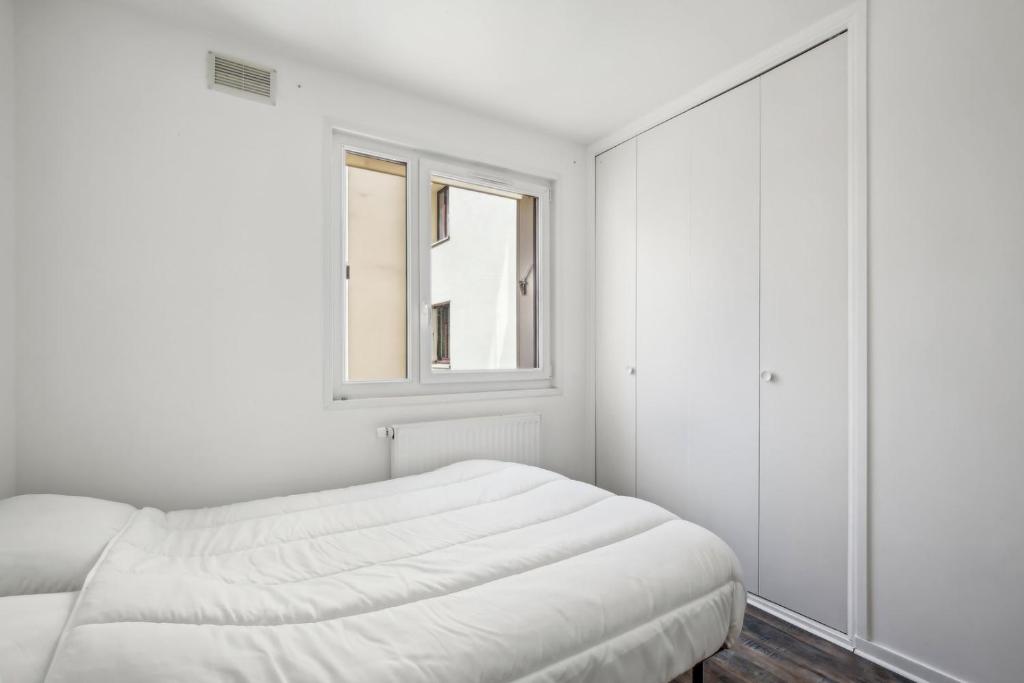 una camera bianca con un letto e una finestra di Le Montigny Chic a Montigny-le-Bretonneux