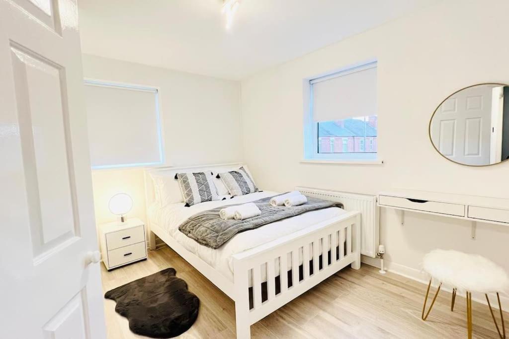 a white bedroom with a bed and a mirror at New fully furnished cosy home in Balderton