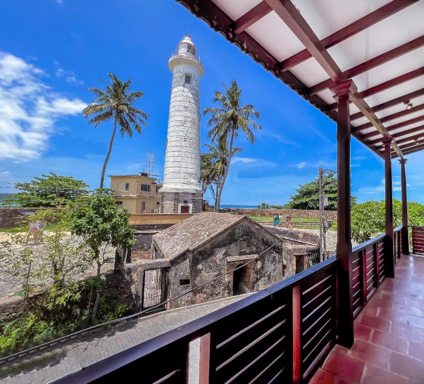 a lighthouse on the beach with palm trees in the background at Light House View Inn - Galle Fort in Galle