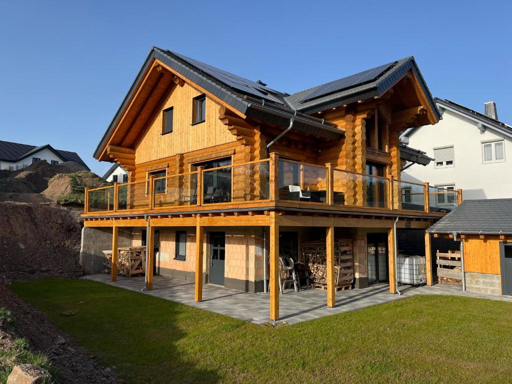 een groot houten huis met een groot terras bij Ferienwohnung Uplandblockhaus in Willingen