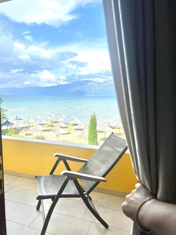 een stoel op een balkon met uitzicht op de oceaan bij Hotel KASHTA in Pogradec