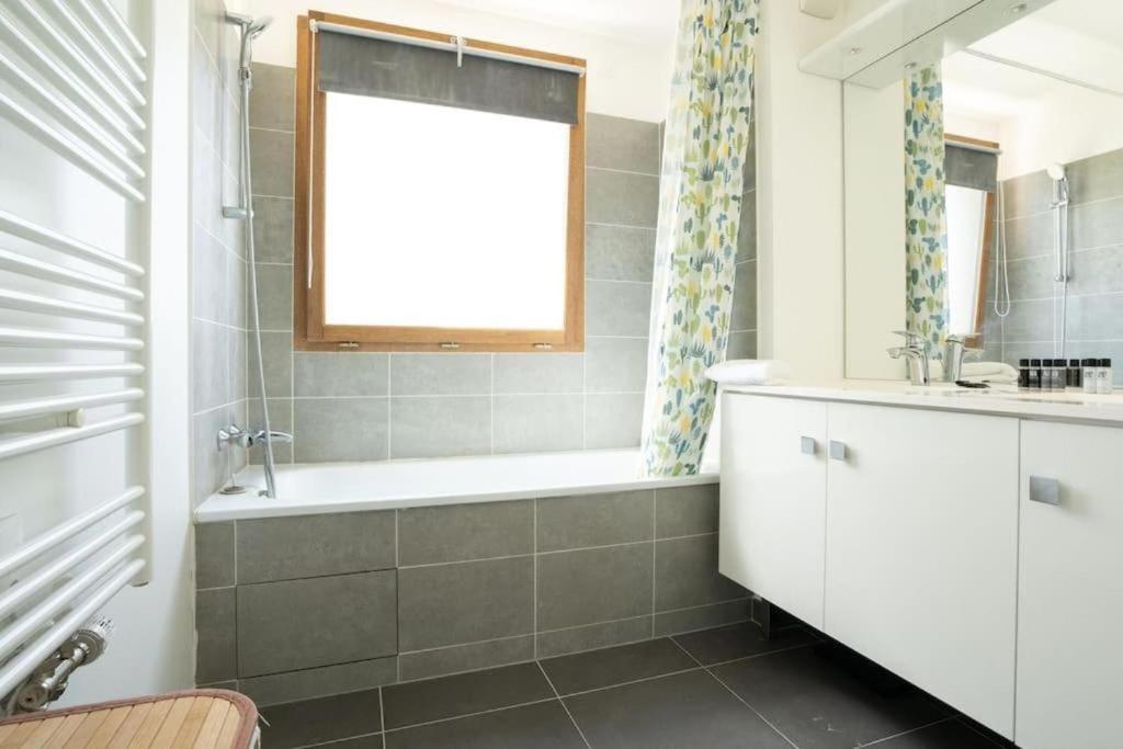 ein Bad mit einer Badewanne und einem Fenster in der Unterkunft Spacieux appartement - Stade de France in Saint-Denis