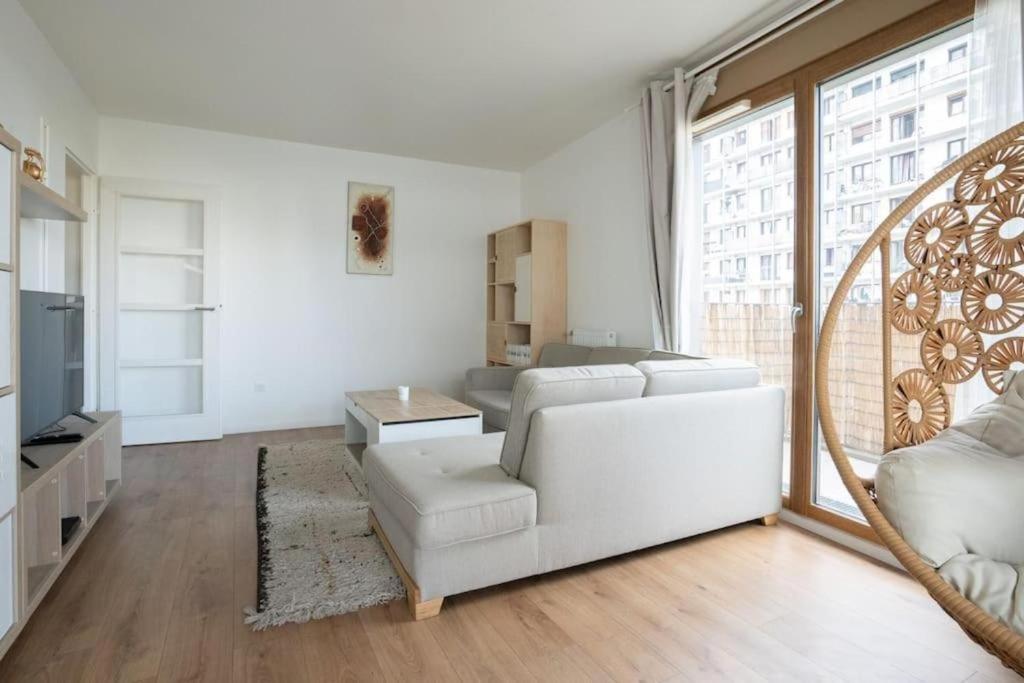 ein Wohnzimmer mit einem weißen Sofa und einem großen Fenster in der Unterkunft Spacieux appartement - Stade de France in Saint-Denis