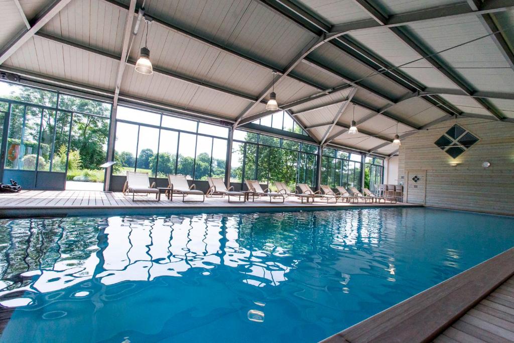 a large swimming pool with chairs in a building at Le Clos de Grâce in Honfleur
