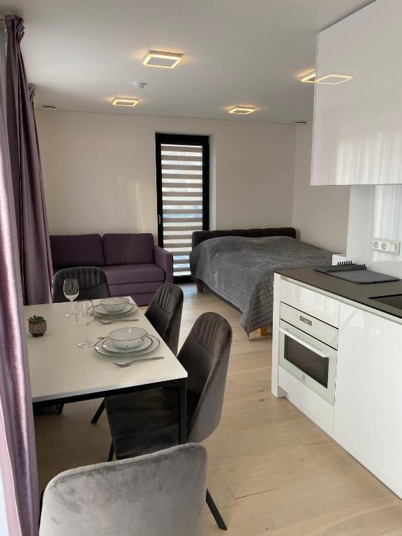 a kitchen and living room with a table and a bed at Ievos apartamentai in Pervalka