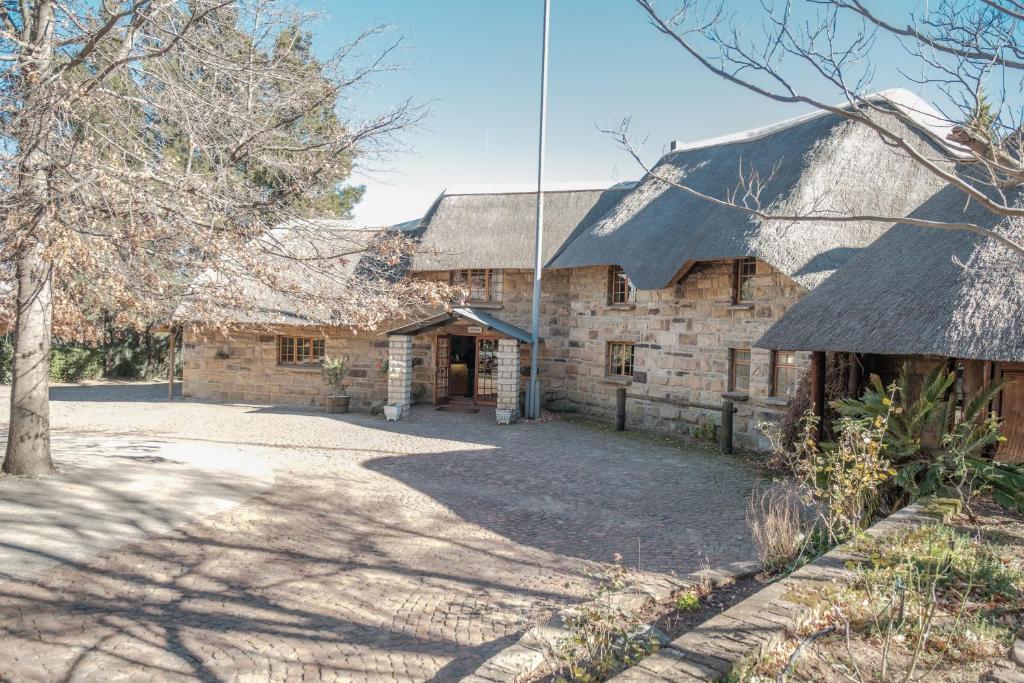 an old stone house with a thatched roof at La La Nathi Country Guesthouse in Harrismith