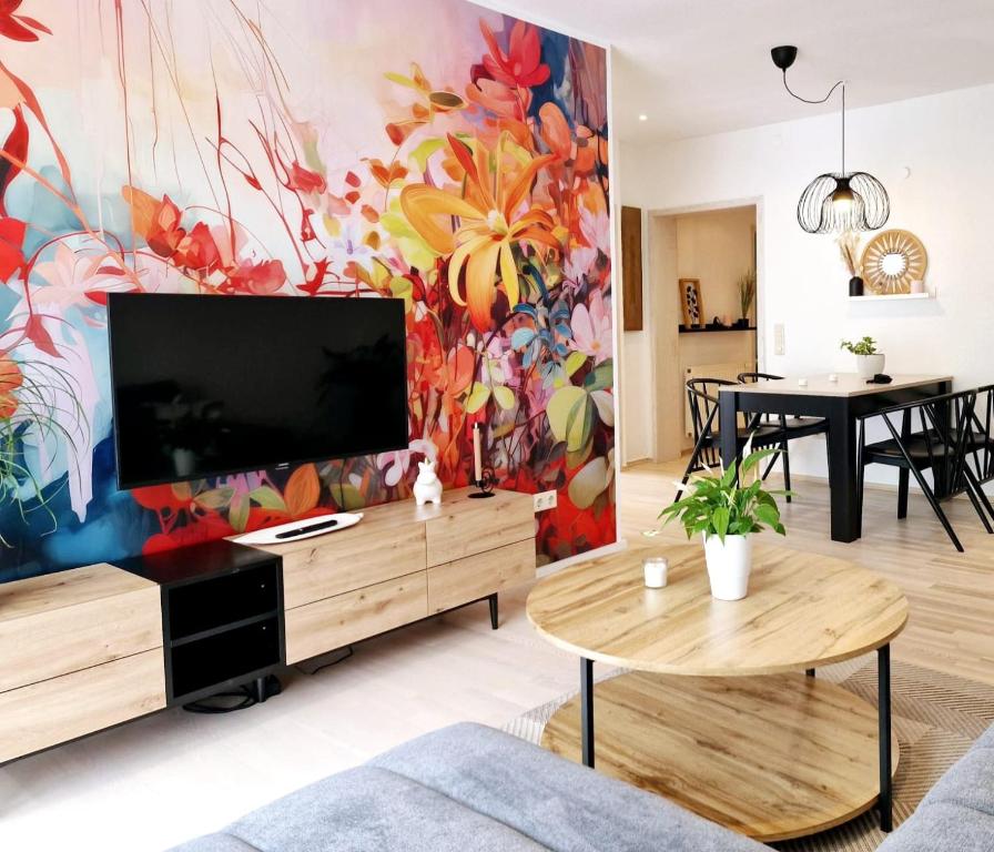 a living room with a large television and a colorful wall at Ferienwohnungen Krüger 'Apartment Marina' in Gammelsbach